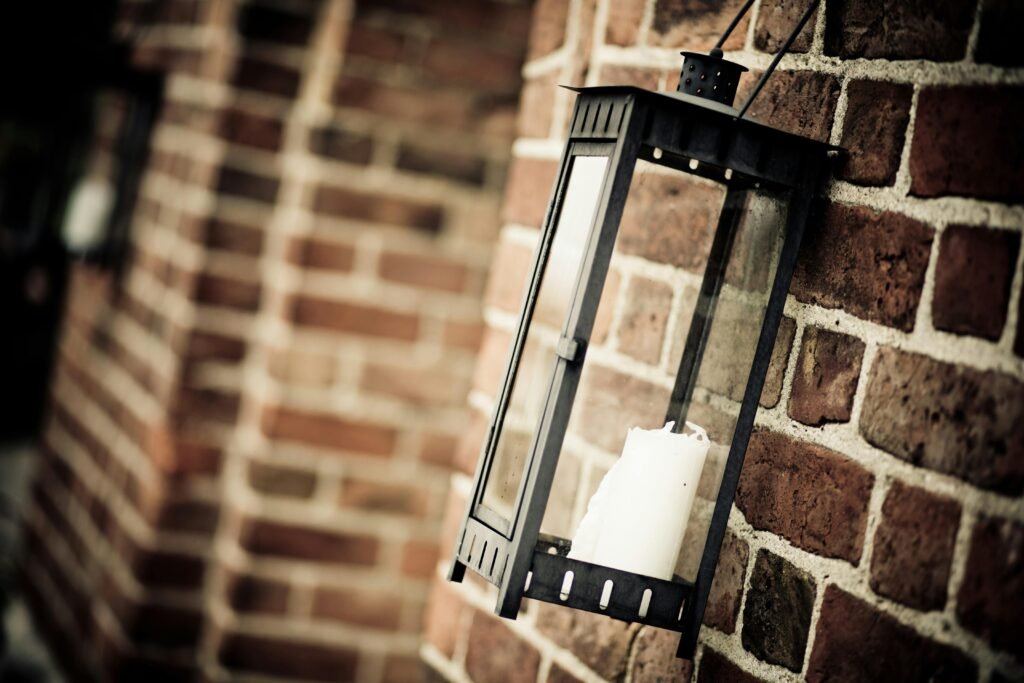 Close-up of a rustic metal lantern hanging on a brick wall, outdoors.